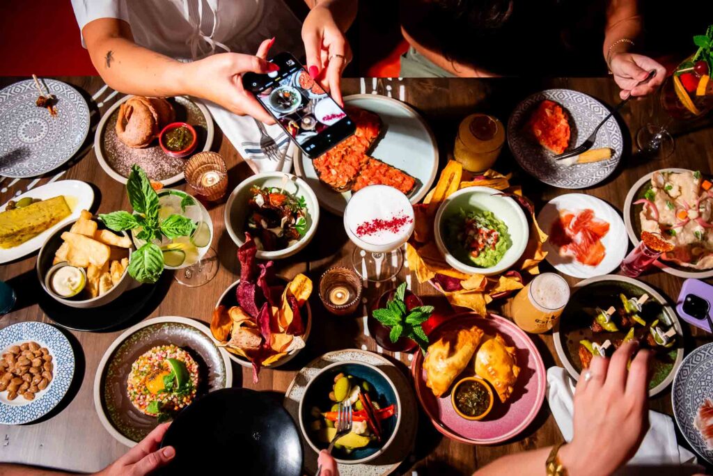 Top down photo of a group of people sharing an assortment of small plates and cocktails at Ceci Bar in Toronto.